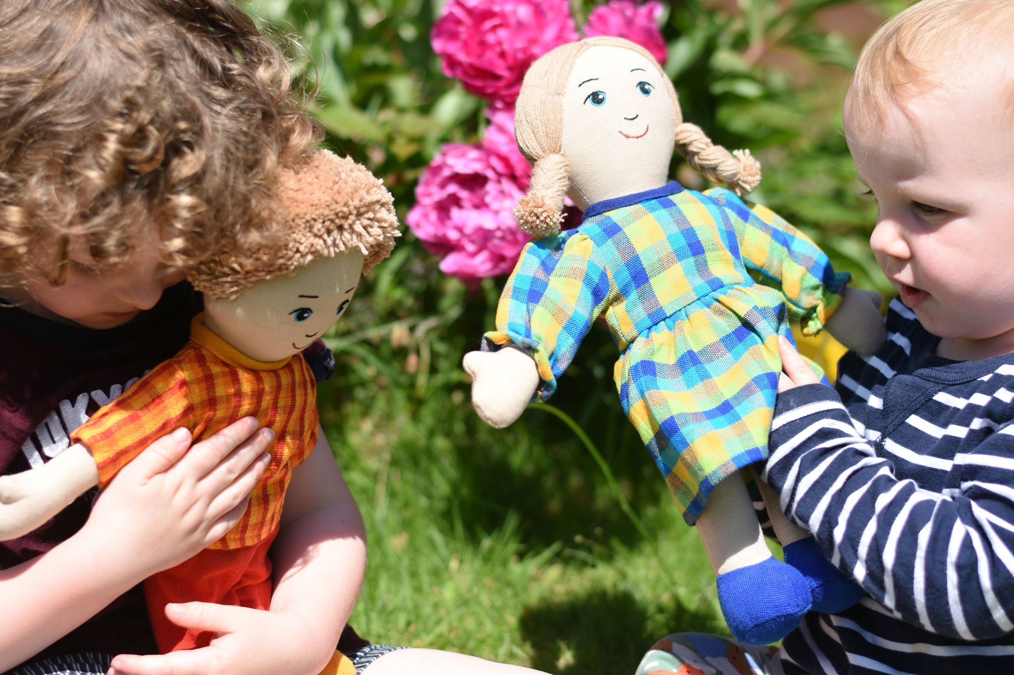 Children playing with Lanka Kade rag dolls in a garden.