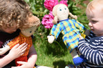 Children playing with Lanka Kade rag dolls in a garden.