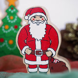 Lanka Kade handcrafted wooden toy figure of Santa Claus, painted in traditional red and white attire with a black belt and boots, holding a brown sack.