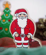 Lanka Kade handcrafted wooden toy figure of Santa Claus, painted in traditional red and white attire with a black belt and boots, holding a brown sack.
