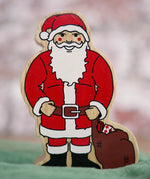 Lanka Kade handcrafted wooden toy figure of Santa Claus, painted in traditional red and white attire with a black belt and boots, holding a brown sack.
