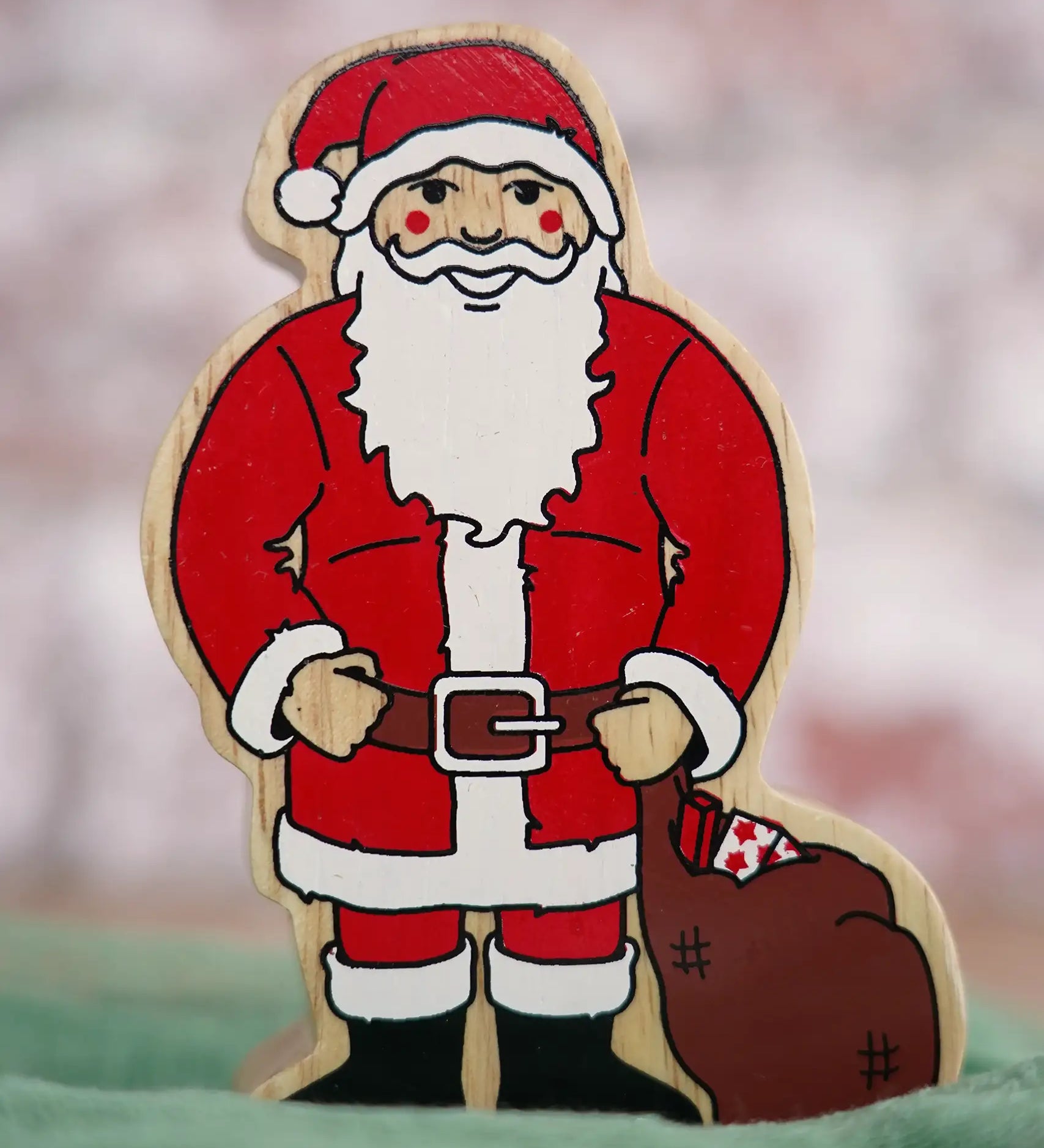 Lanka Kade handcrafted wooden toy figure of Santa Claus, painted in traditional red and white attire with a black belt and boots, holding a brown sack.