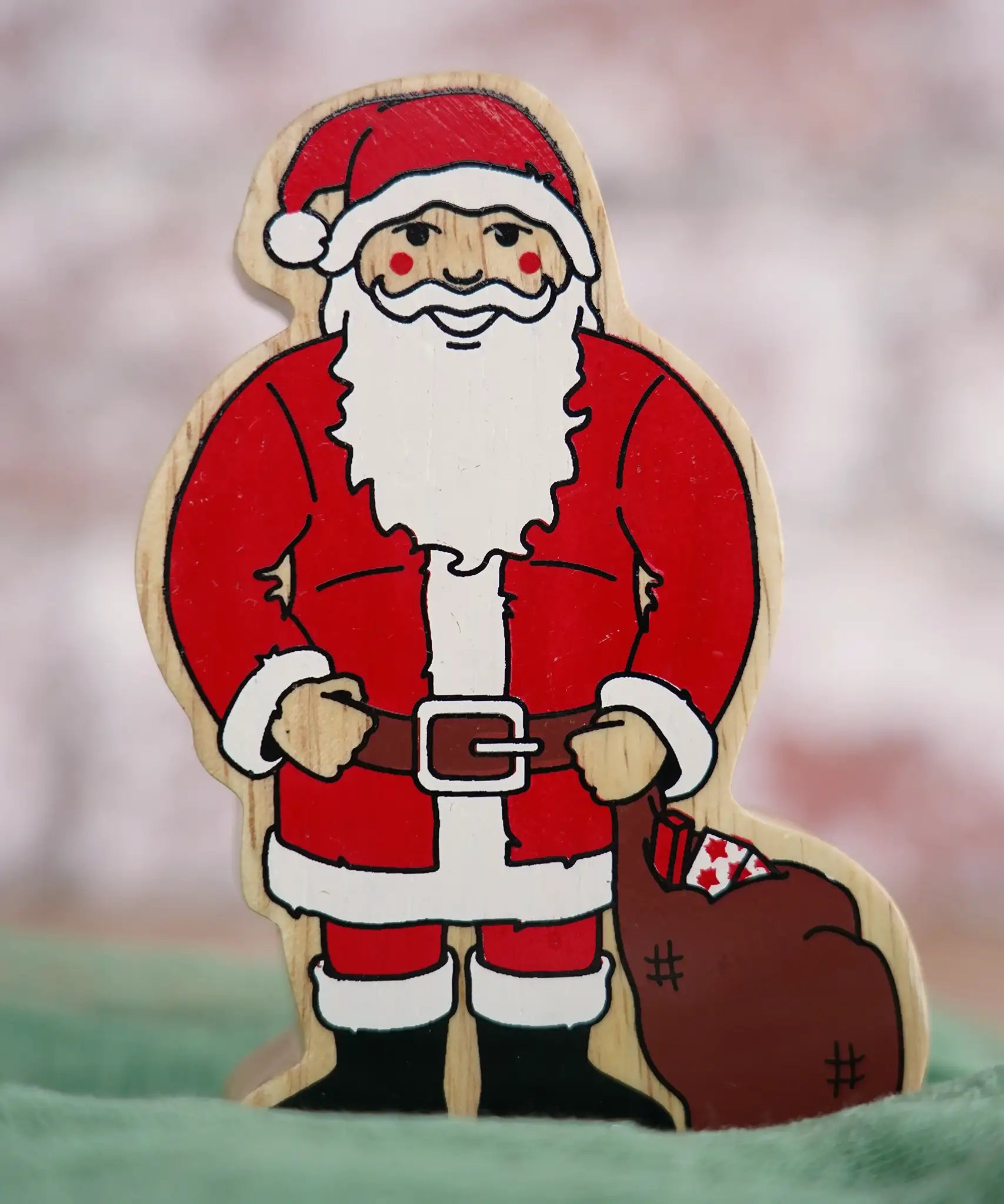 Lanka Kade handcrafted wooden toy figure of Santa Claus, painted in traditional red and white attire with a black belt and boots, holding a brown sack.