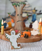 A Lanka Kade wooden toy ghost figure placed in front of a Halloween themed Grimm's celebration ring set up.