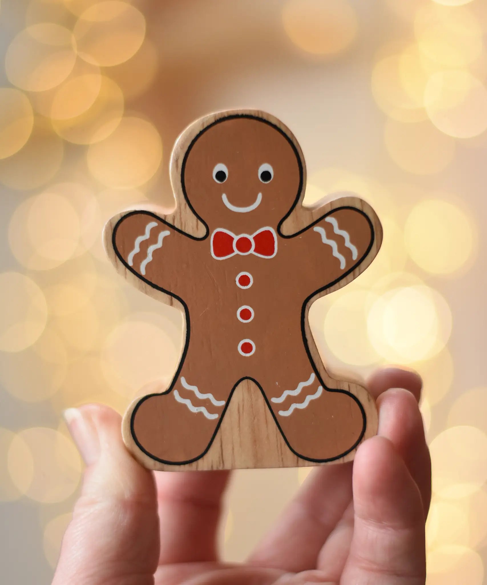Lanka Kade gingerbread man wooden toy figure in an adult's hand.