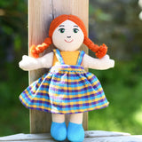 A Lanka Kade Girl Doll with White Skin and Red Hair leaning against a wooden post outdoors.