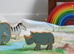 A Lanka Kade Grey Rhino Wooden Wild Animal Figure placed on a Wonderie Plains of Africa play cloth. An elephant and zebra figure can be seen in the background. 
These wooden toy figures are part of a huge range of Lanka Kade fair trade, wooden toys available here at Babipur.