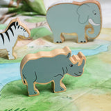 A Lanka Kade Grey Rhino Wooden Wild Animal Figure placed on a Wonderie Plains of Africa play cloth. An elephant and zebra figure can be seen in the background. 
These wooden toy figures are part of a huge range of Lanka Kade fair trade, wooden toys available here at Babipur.