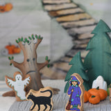 A Lanka Kade black cat and witch figures placed at the front of a small world play scene. 