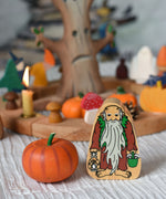 A Lanka Kade Hermit wooden toy figure placed next to an Erzi pumpkin. 