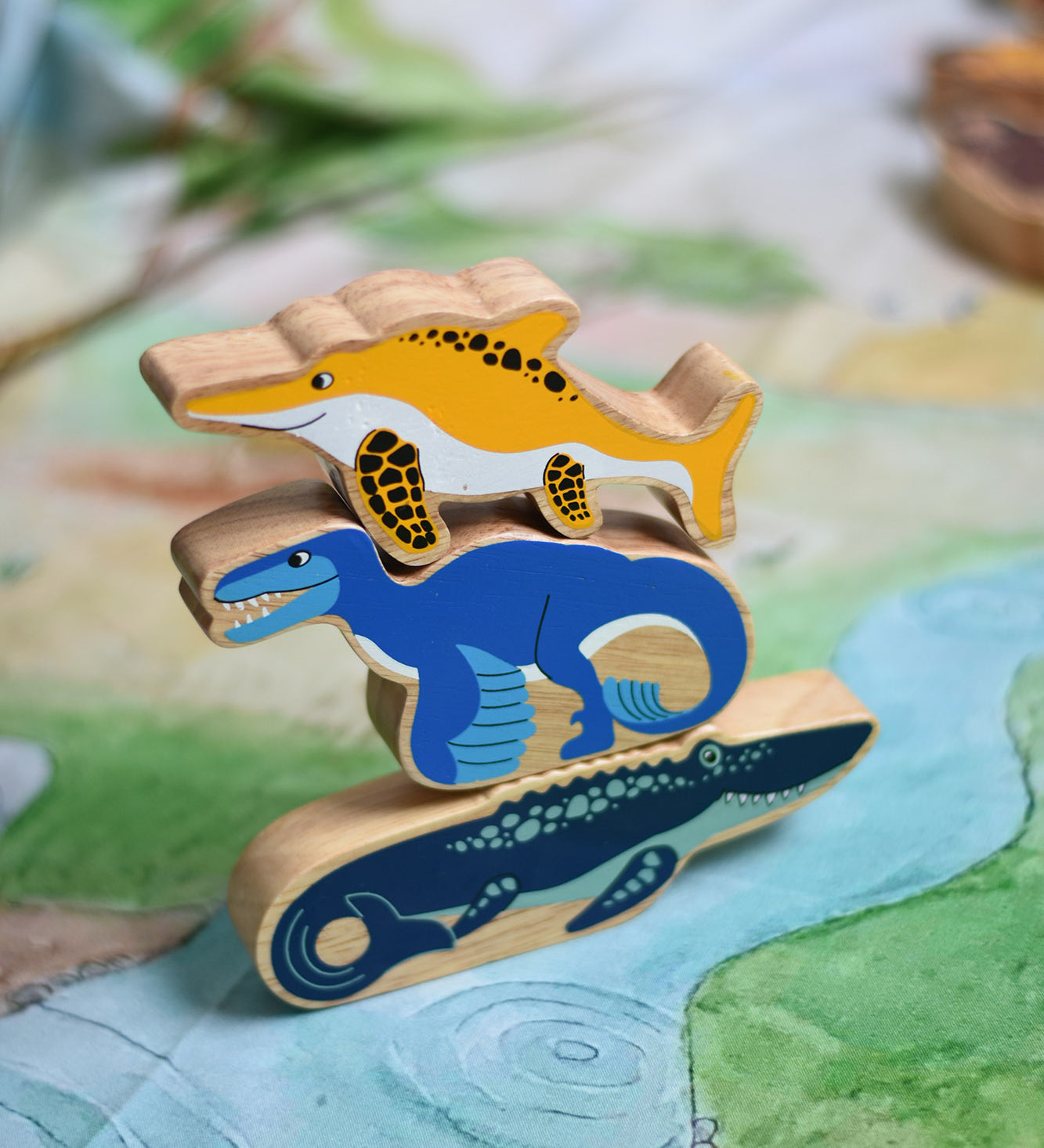 A stack of Lanka Kade toy figures with the icthyosaur placed on top of a utahraptor and mososaurus. These wooden toy figures are part of a huge range of Lanka Kade fair trade, wooden toys available here at Babipur.