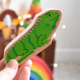 A Lanka Kade green iguana wooden toy figure placed in an adult's hand. These wooden toy figures are part of a huge range of Lanka Kade fair trade, wooden toys available here at Babipur.