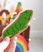 A Lanka Kade green iguana wooden toy figure placed in an adult's hand. These wooden toy figures are part of a huge range of Lanka Kade fair trade, wooden toys available here at Babipur.