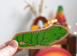 A Lanka Kade green iguana wooden toy figure placed in an adult's hand. These wooden toy figures are part of a huge range of Lanka Kade fair trade, wooden toys available here at Babipur.