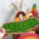 A Lanka Kade green iguana wooden toy figure placed in an adult's hand. These wooden toy figures are part of a huge range of Lanka Kade fair trade, wooden toys available here at Babipur.