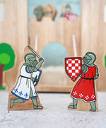 Lanka Kade wooden red foot knight standing next to a blue knight with raised sword figure in front of a wooden castle