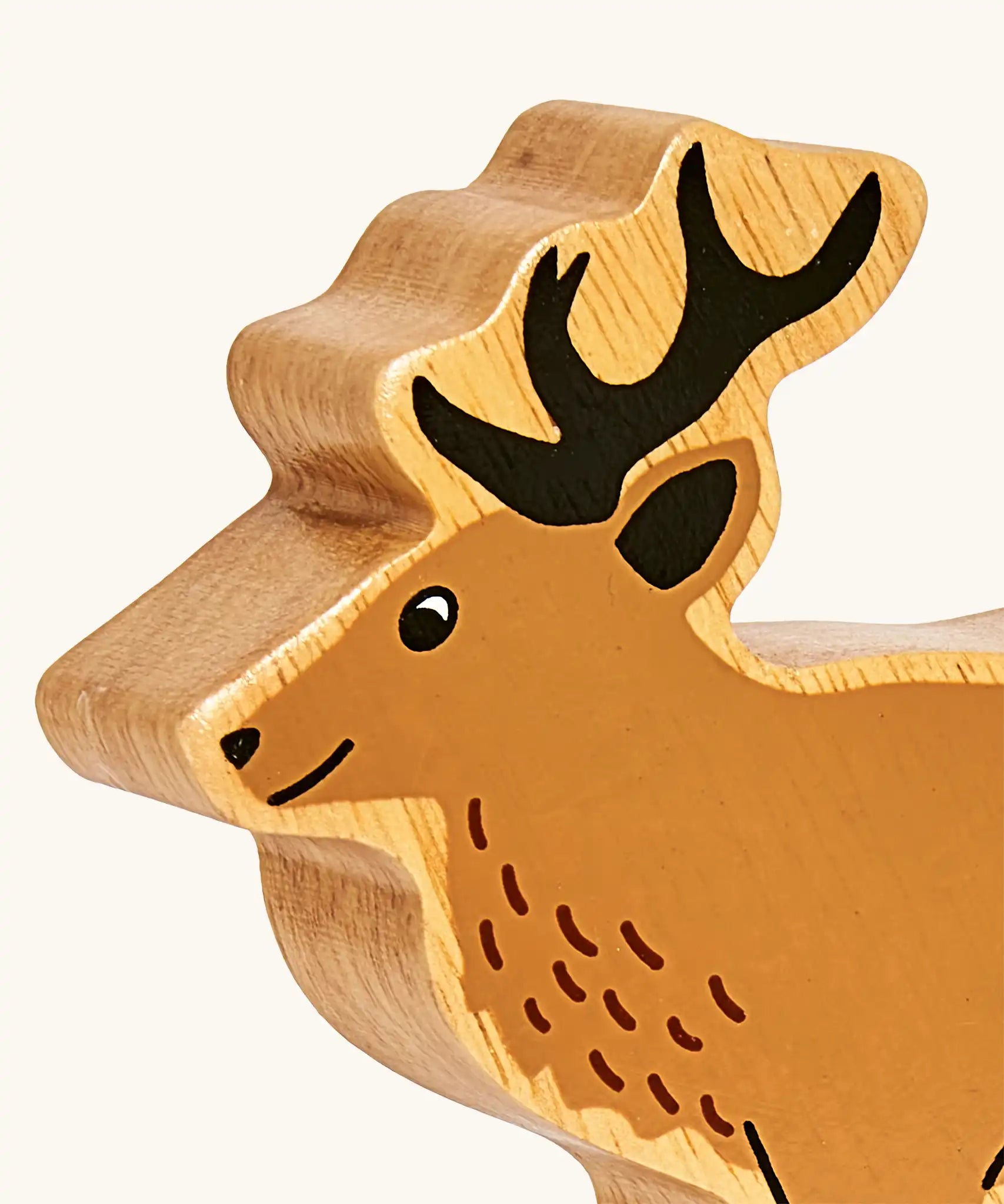 Close up of painted facial features on the Lanka Kade light brown stag wooden toy figure.