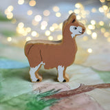 A Lanka Kade brown and white Llama wooden toy figure placed on a Wonderie play cloth. These wooden toy figures are part of a huge range of Lanka Kade fair trade, wooden toys available here at Babipur.