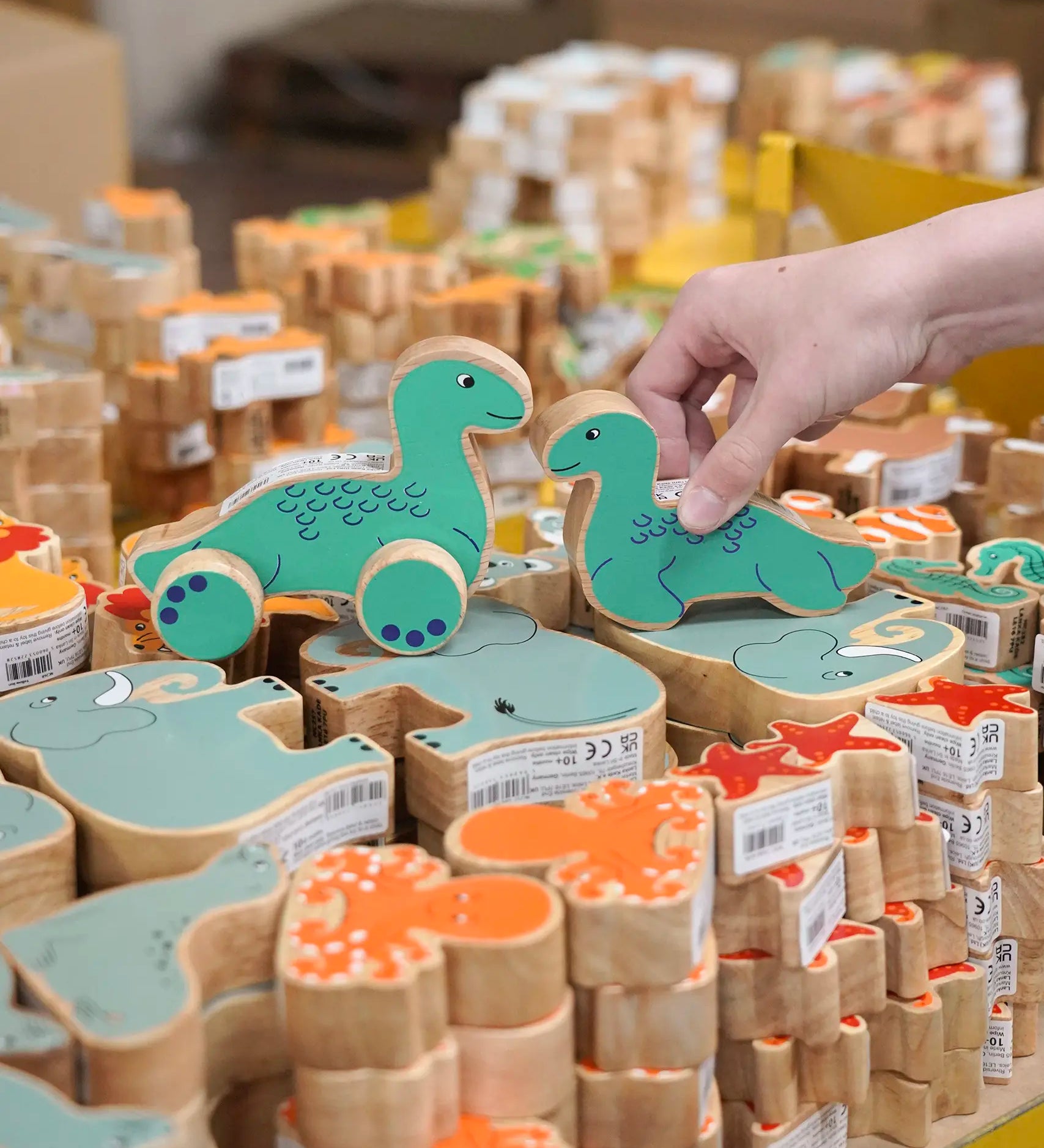 Lanka Kade Nessie push-along and Nessie wooden toy figure placed on stacks of other Lanka Kade animal figures.