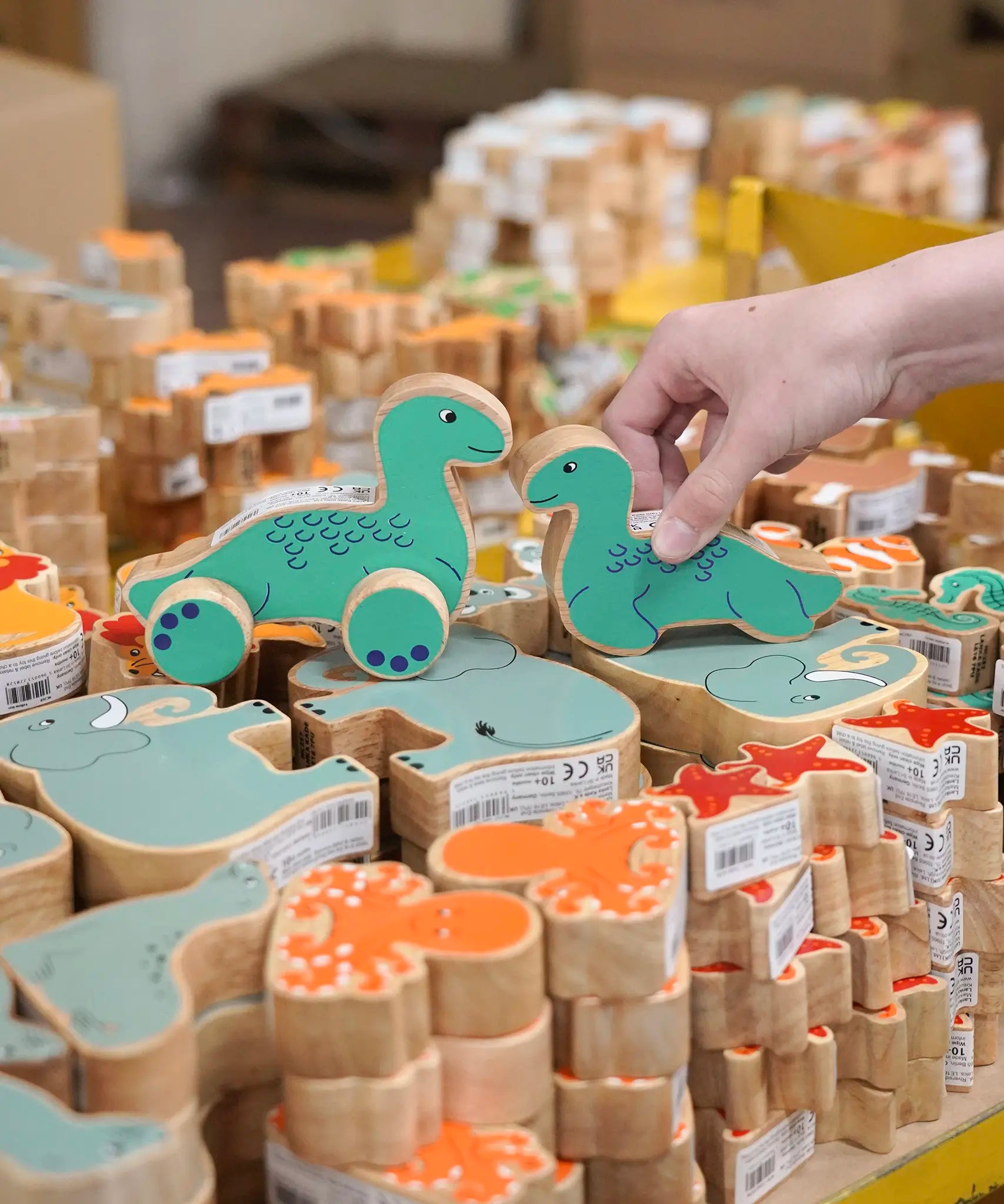 Lanka Kade Nessie push-along and Nessie wooden toy figure placed on stacks of other Lanka Kade animal figures.