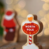 Lanka Kade North Pole sign wooden toy figure. Red snow toped sign with yellow top and striped pole.