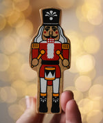 Lanka Kade nutcracker Christmas wooden toy figure in an adult's hand.