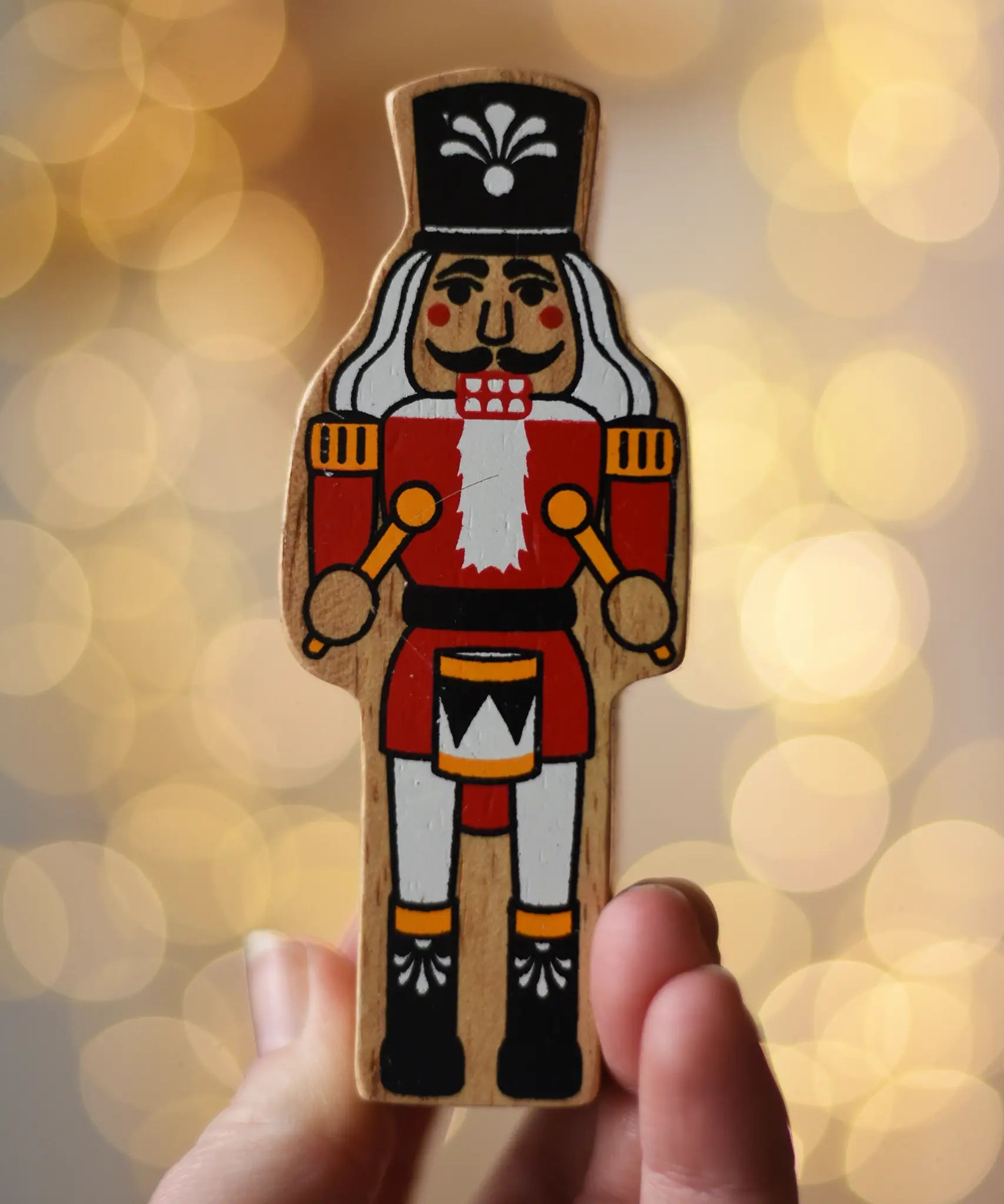 Lanka Kade nutcracker Christmas wooden toy figure in an adult's hand.