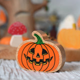 A close up of an orange pumpkin wooden toy figure. 