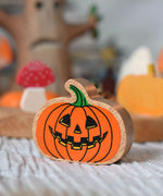 A close up of an orange pumpkin wooden toy figure. 