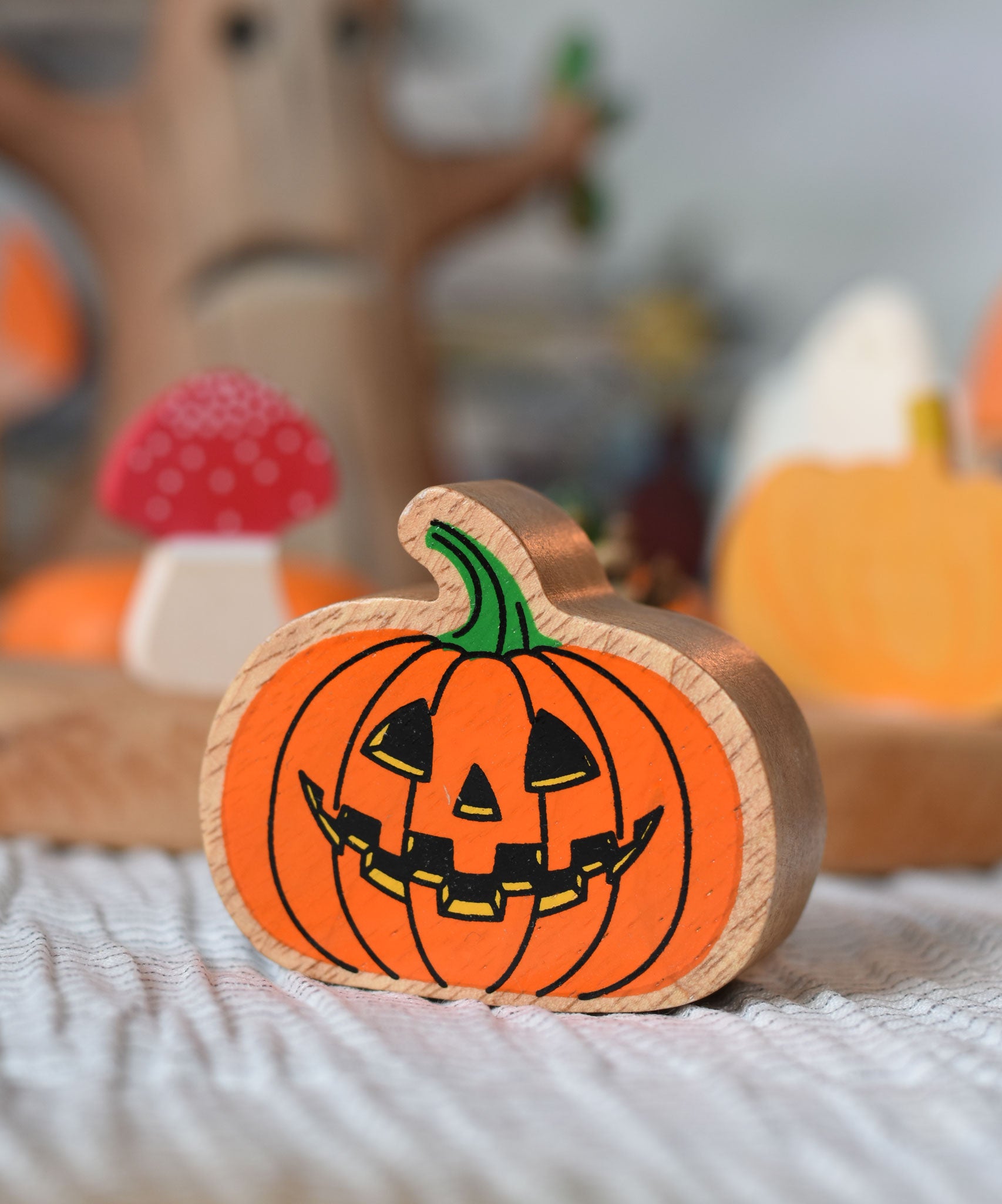 A close up of an orange pumpkin wooden toy figure. 