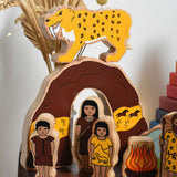 The Lanka Kade Prehistoric Playset set up on a small wooden table. A play set that contains 8 wooden figure and scenery pieces. These wooden toy figures are part of a huge range of Lanka Kade fair trade, wooden toys available here at Babipur.
