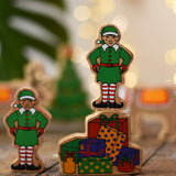 Lanka Kade Christmas presents wooden toy figure with an elf figure standing on top placed on a wooden surface in the Babipur playroom.