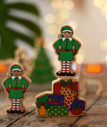 Lanka Kade Christmas presents wooden toy figure with an elf figure standing on top placed on a wooden surface in the Babipur playroom.