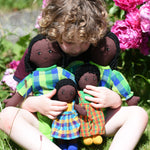 A child cuddling a family ofLanka Kade Rag Dolls with Black Skin and Black Hair.