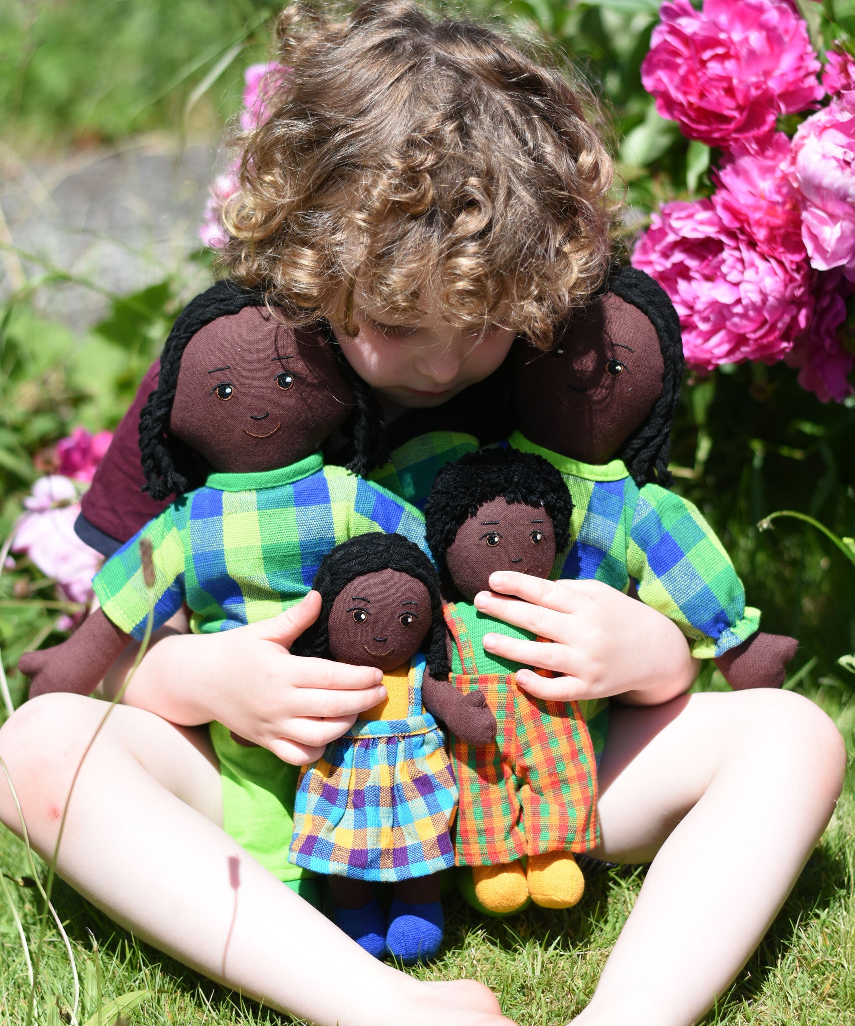 A child cuddling a family ofLanka Kade Rag Dolls with Black Skin and Black Hair.