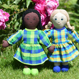 Two Lanka Kade Rag Doll Mums one with black hair and black skin White Skin, Blonde Hair placed on grass in front of peonies growing in a garden.