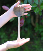 A coconut shell rake shown in a child's hand. These coconut shell utensils are a welcome addition to our range of outdoor toys here at Babipur. 