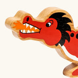 Close-up of the Lanka Kade wooden toy dragon in red showing painted facial features, orange mouth flame.
