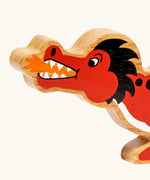 Close-up of the Lanka Kade wooden toy dragon in red showing painted facial features, orange mouth flame.