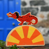 Lanka Kade red dragon wooden toy dragon figure with black details placed on a yellow and orange Babipur sun. 