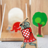 Lanka Kade red knight with raised sword figure with a wooden castle, trees and Babipur elephant figure in the background.