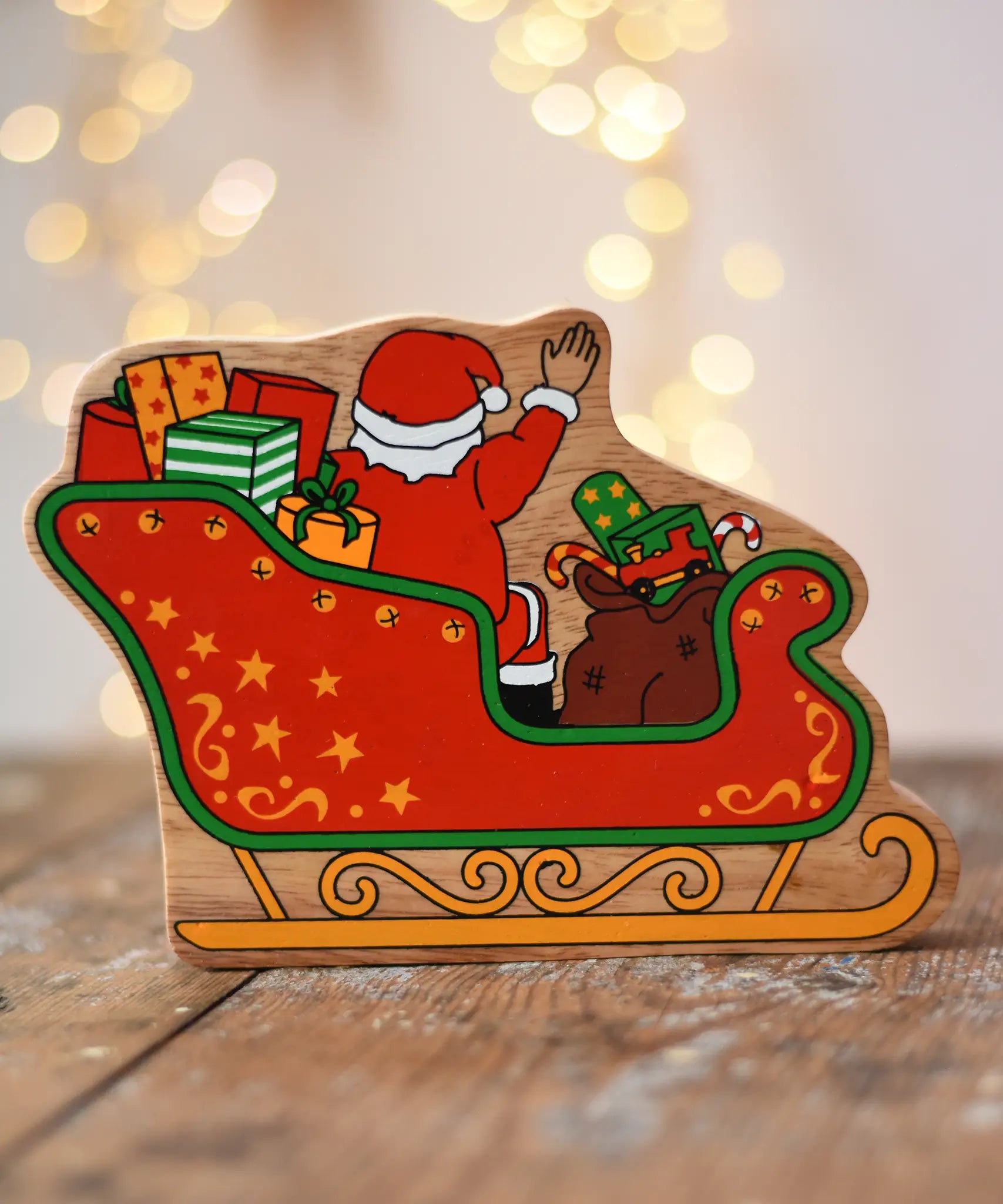Back of the Lanka Kade Father Christmas in a sleigh wooden toy figure. The back features Santa sitting in the sleigh waving, surrounded by gifts. 