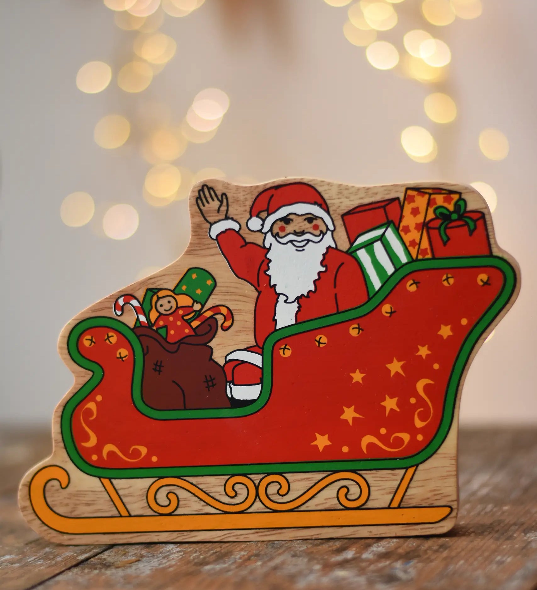 Lanka Kade Father Christmas in a sleigh wooden toy figure. The front features Santa sitting in the sleigh waving, surrounded by gifts. 