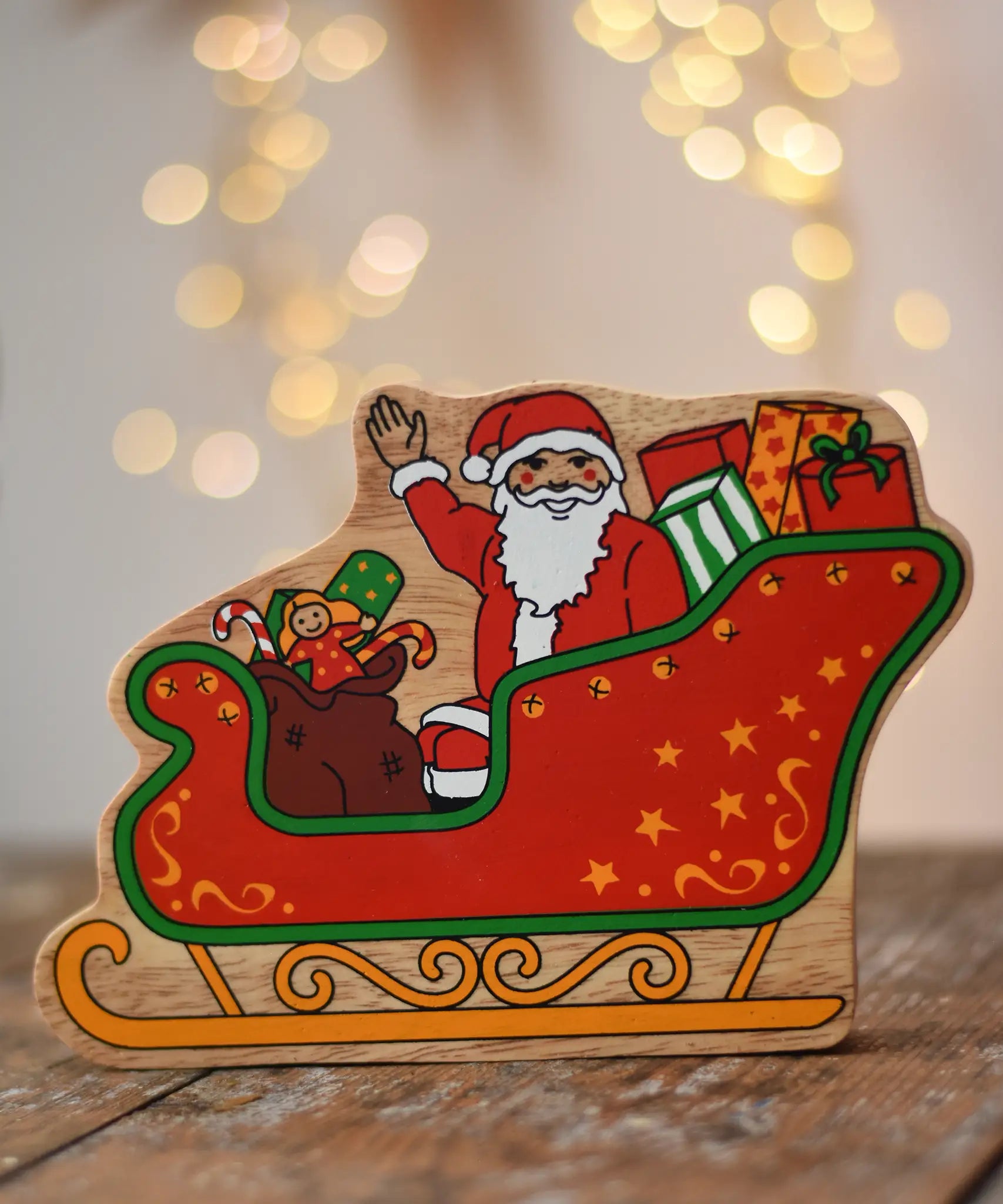 Lanka Kade Father Christmas in a sleigh wooden toy figure. The front features Santa sitting in the sleigh waving, surrounded by gifts. 