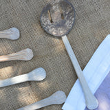 A close up of on of the utensils from the Lanka Kade coconut shell utensil set. The mesh storage bag that the set comes in can be seen to one side along with the handles from other utensils.