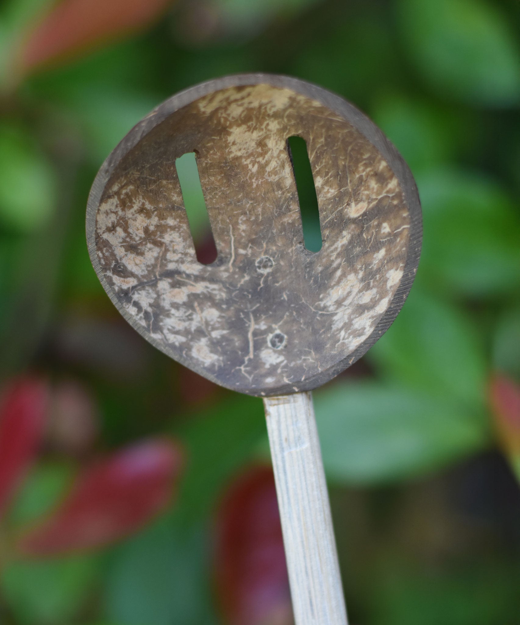 A close up of the front of a slotted spoon from the range of coconut shell utensils from  Lanka Kade. 