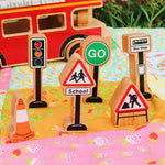 Close up of the Lanka Kade small world town accessories play set on a colourful blanket next to a toy bus