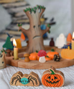 A Lanka Kade spider and pumpkin wooden toy figure placed in front of an Autumnal themed celebration ring set up.