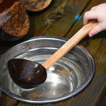 A close up of a Lanka Kade ladle spoon utensil being used in water.