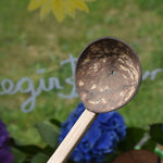 A close up of the coconut shell spoon with one hole from the utensil playset from Lanka Kade.